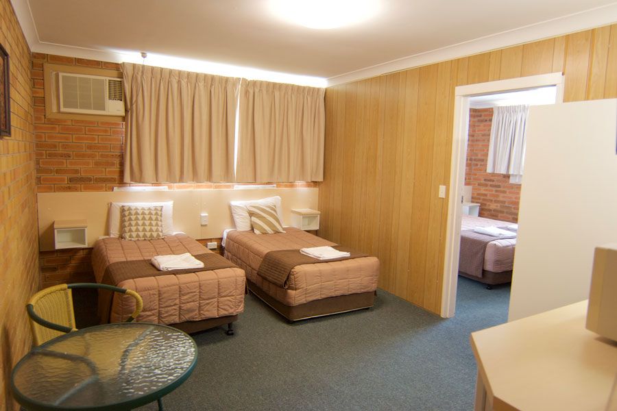 A room with brown room with brown wooden divider that separate the two single beds and one queen bed